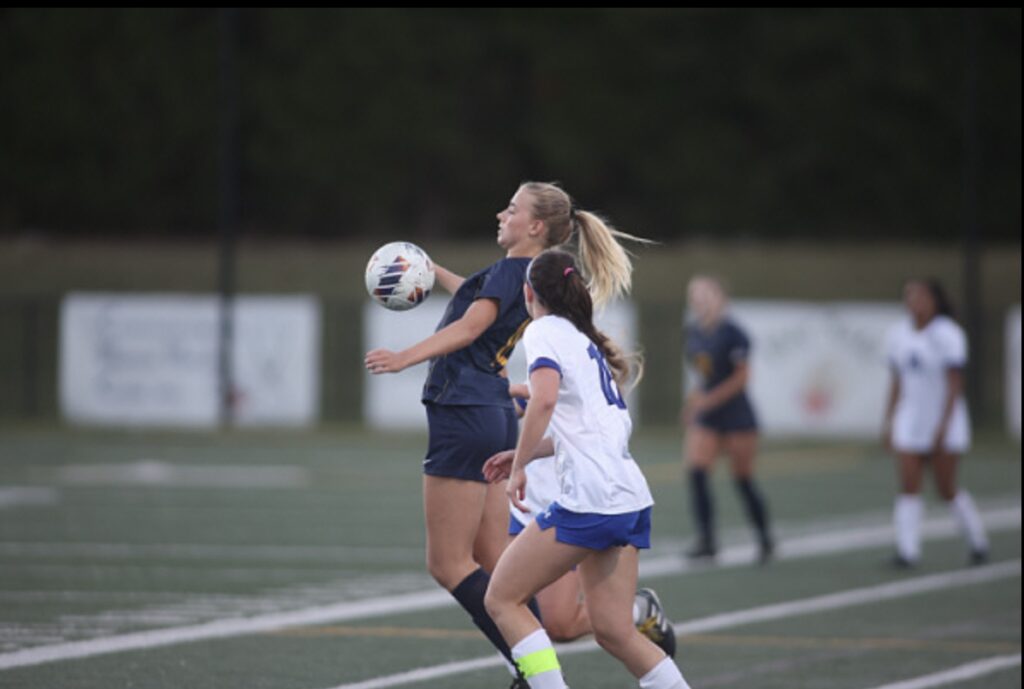 Two female college soccer players on soccer field