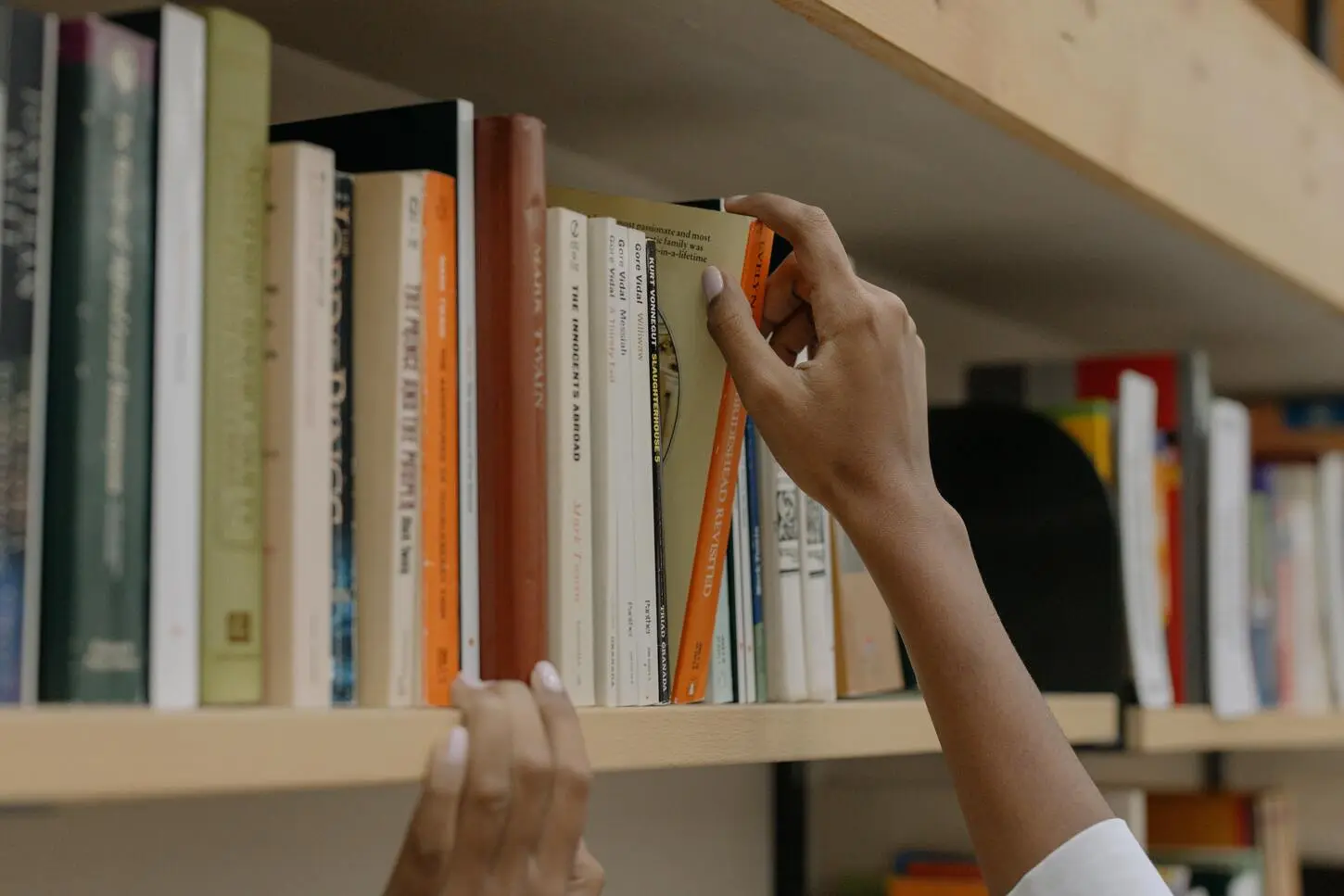 hand reaches for books on the bookshelf