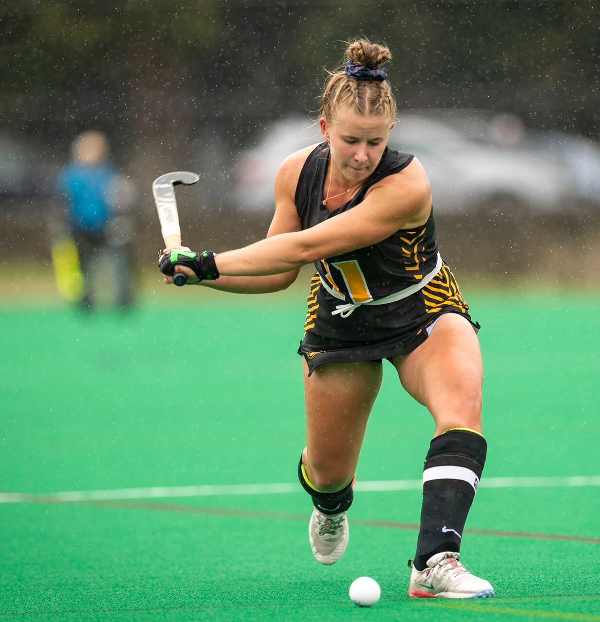 A female hockey player about to hit the ball