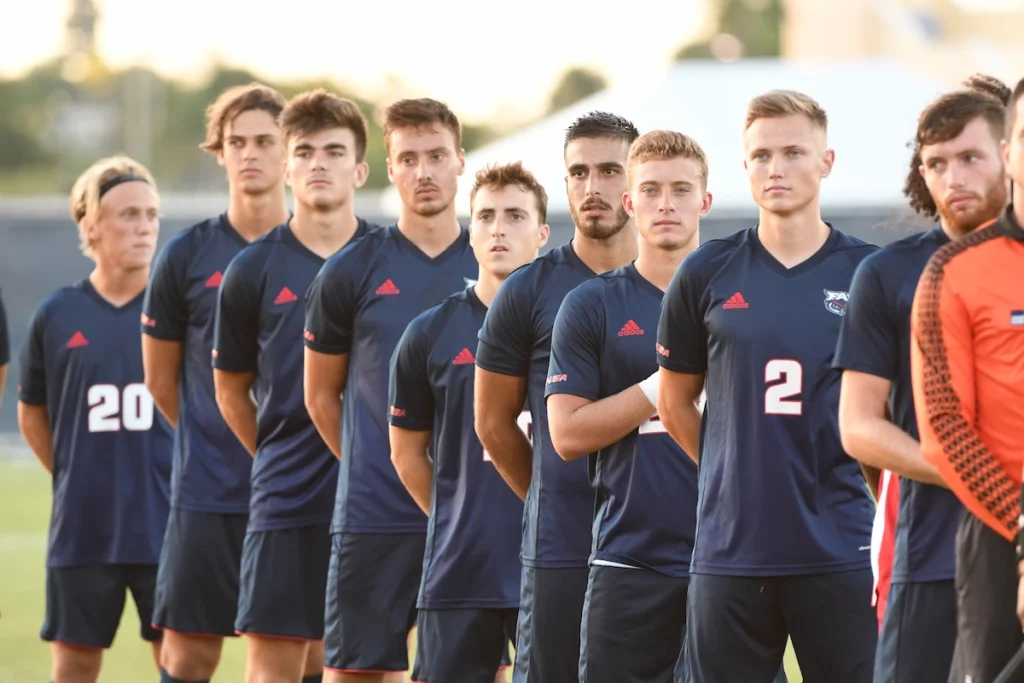 Collegefotbollslag sjunger nationalsången.
